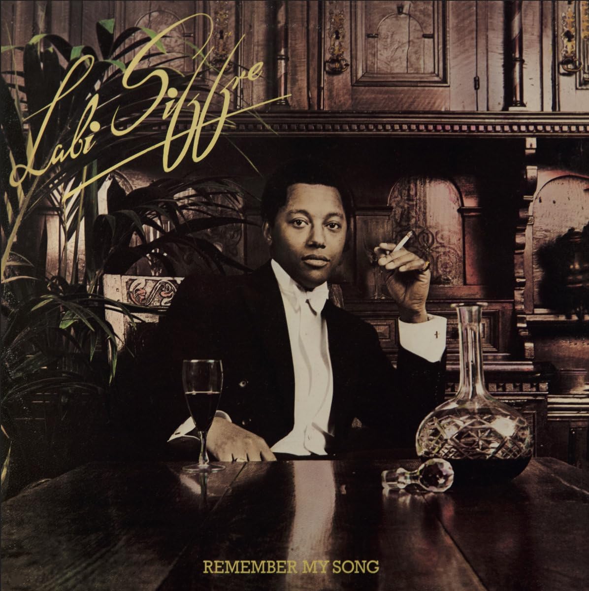 Album cover with a person sitting at a table with a glass and decanter, text 'Lali Giffith' and 'Remember My Song'.