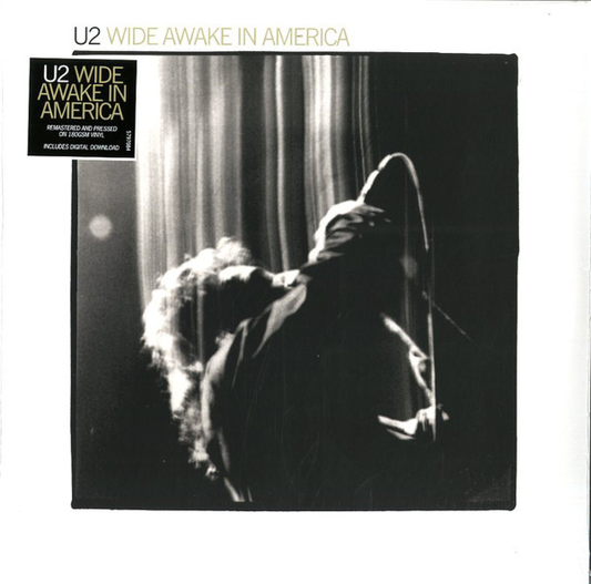 U2 - Wide Awake In America album cover, featuring a black and white photo of Bono performing on stage with a microphone and the album title text.