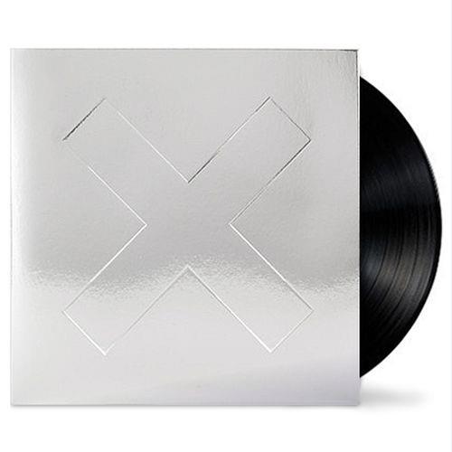A vinyl LP of The XX album 'I See You', with a white cover featuring a silver x.
